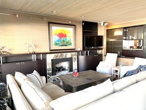 A modern living room with a fireplace, a flat-screen TV, and a dining area.