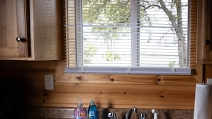 A kitchen with wooden cabinets, a granite countertop, a double sink, and a window with blinds. - Cottage 1 on Beautiful Fox Lake! (Fox Lake)