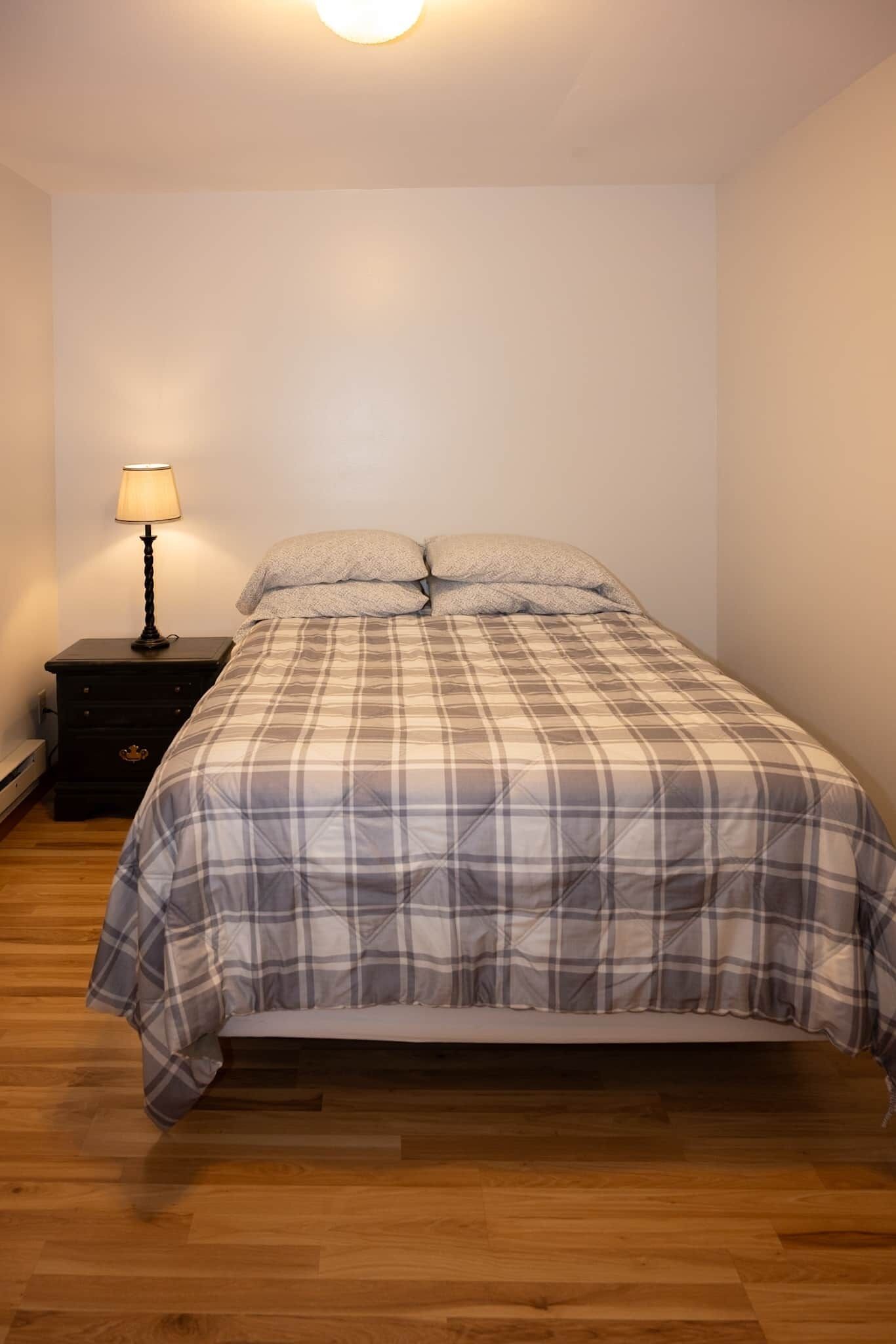 Ein Schlafzimmer mit Bett, Nachttisch und Lampe.