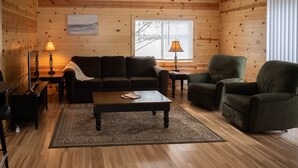 A cozy living room with a wooden interior, a sofa, a coffee table, and two lamps.