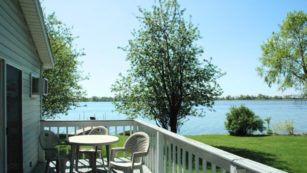 A deck with a table and chairs overlooking a lake.