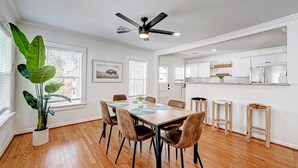 Une cuisine moderne avec des armoires blanches, un îlot central et un ventilateur de plafond.
