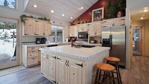 Une cuisine moderne avec des meubles en bois, un grand îlot central et un réfrigérateur en acier inoxydable.