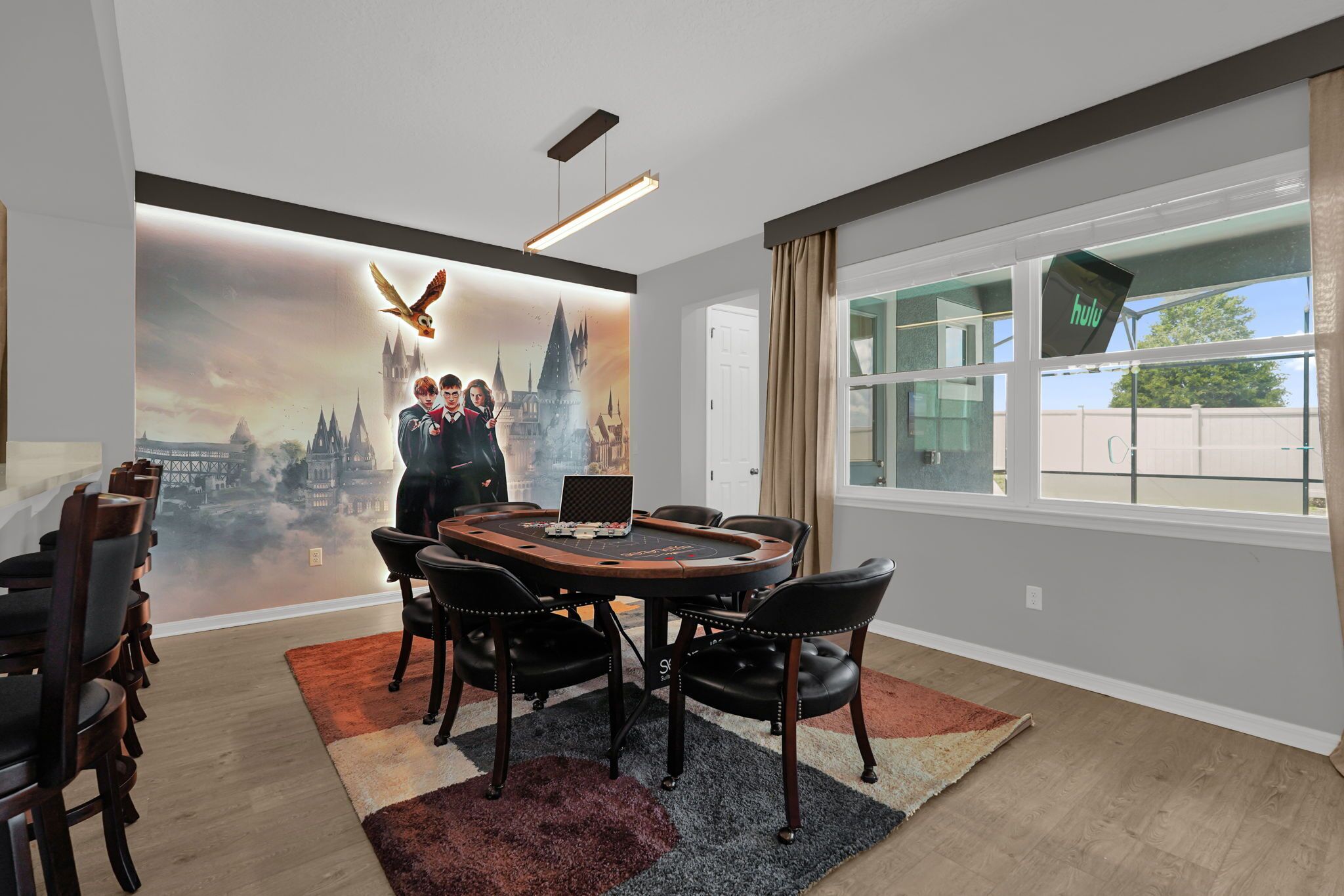 A conference room with a round table, chairs, a laptop, and a large wall mural.