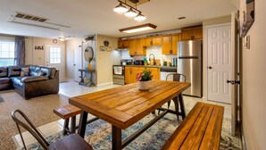 Eine moderne Küche mit Holzschränken, einem Edelstahlkühlschrank und einem Essbereich mit Holztisch und Bänken.