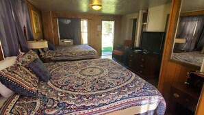 A bedroom with a large bed, a dresser, a television, and a door leading outside.