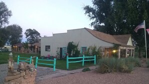 A white building with a brown roof, a turquoise fence, and an American flag.