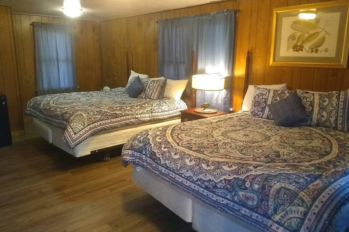 Ein Zimmer mit zwei Betten, Holzwänden und einem gerahmten Bild an der Wand.