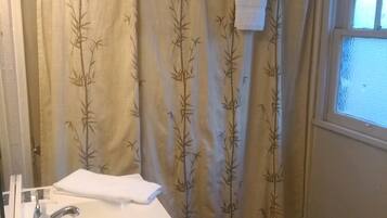 A bathroom with a shower curtain featuring a bamboo pattern, a white sink with a mirror, and a toilet.