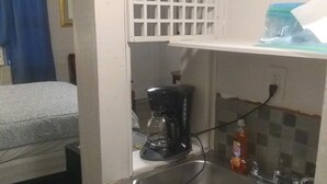 A compact kitchenette with a sink, a coffee maker, and a bottle of dish soap.