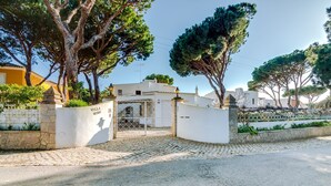 Una villa llamada "Villa Mimi" con entrada de adoquines, paredes blancas y un camino de acceso con portón.