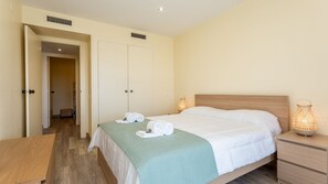 A hotel room with a bed, bedside table, and two wall-mounted lamps.