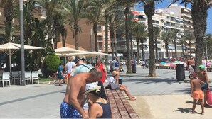 Une place publique agrémentée de palmiers, de bancs et de parasols.