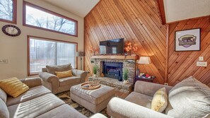 A cozy living room with a fireplace, comfortable seating, and a large window.