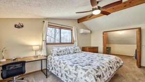 Ein Schlafzimmer mit Bett, Schreibtisch, Stuhl, Deckenventilator und Fenster.