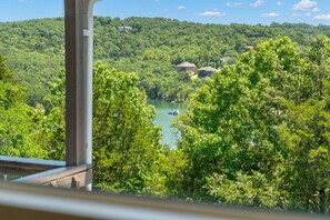 A view of a lake surrounded by dense greenery and hills, with a boat visible on the water. - Secluded Getaway featuring Walking Trail to the Lake, Free Tickets & Minutes from Silver Dollar City (Reeds Spring)