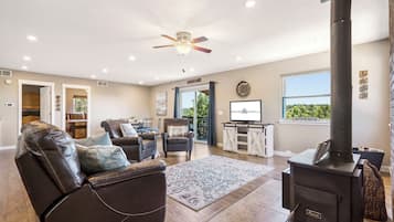 A cozy living room with a fireplace, leather sofas, and a view of the outdoors.