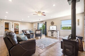 Uma sala de estar aconchegante com lareira, sofás de couro e vista para o exterior.