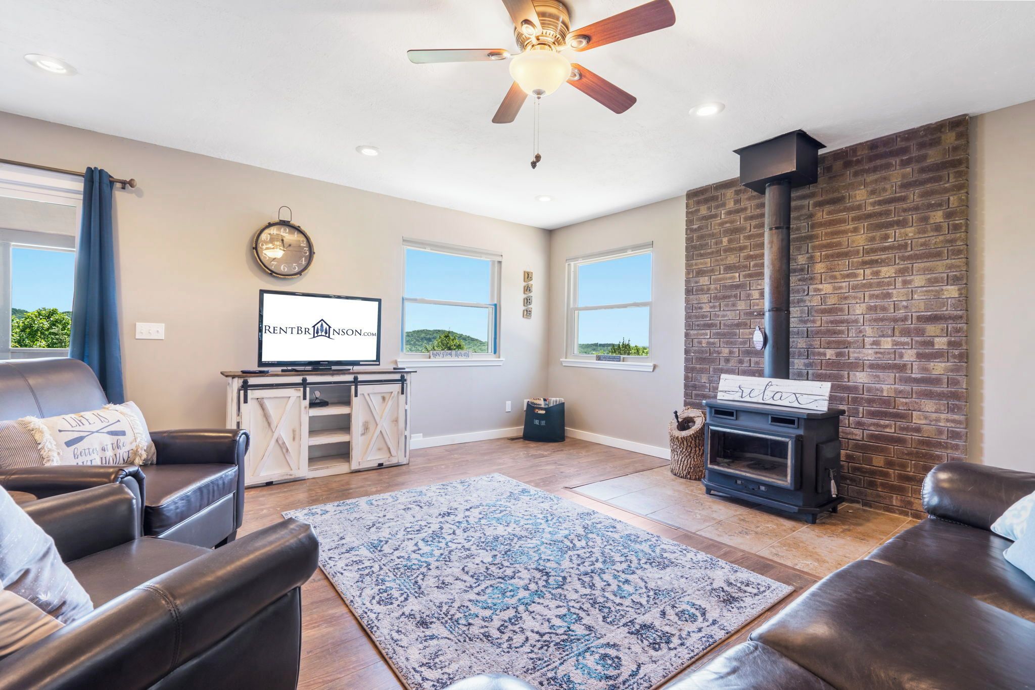 A living room with a fireplace, leather sofas, a television, and a clock on the wall.