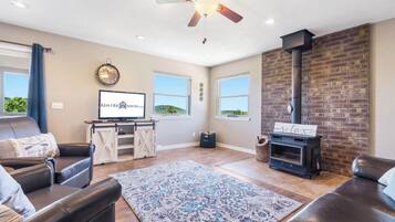 A living room with a fireplace, leather sofas, a television, and a clock on the wall.