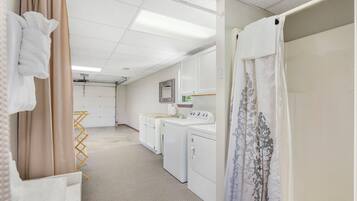 A laundry room with a washing machine, dryer, and ironing station.