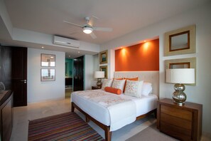 A modern hotel bedroom with a large bed, a ceiling fan, and a nightstand with a lamp.