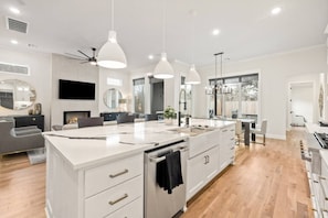 Une cuisine moderne dotée d’un îlot central, de luminaires suspendus et d’une grande fenêtre.