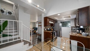 Una cocina moderna con una isla central, electrodomésticos integrados y un comedor con barandillas de vidrio.
