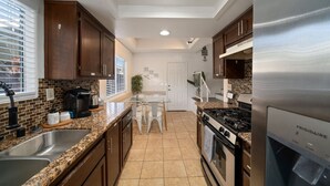 Una cocina con encimeras de granito, electrodomésticos de acero inoxidable y armarios de madera.