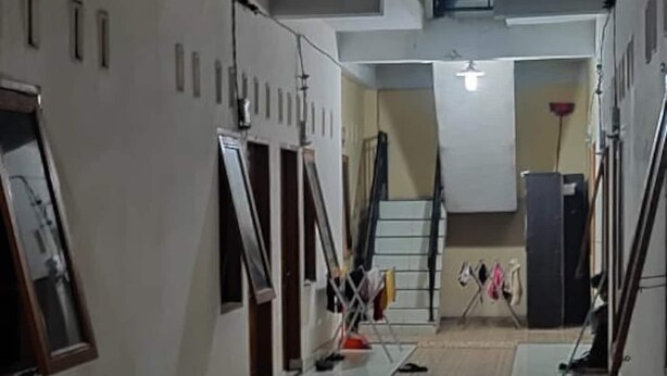 Um corredor com piso de azulejos, escadas e uma varanda com guarda-corpo.