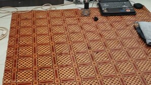 Quarto com guarda-roupa de madeira escura, tapete estampado no chão, um laptop, uma bolsa preta e um capacete verde.