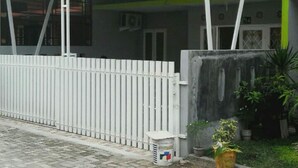 Edifício residencial com varanda coberta, entrada com portão e um pequeno jardim.