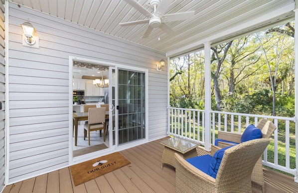 A covered porch with wicker furniture and a sliding glass door leading to a kitchen.