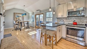 A modern kitchen with a large island, stainless steel appliances, and a view to the outdoors.