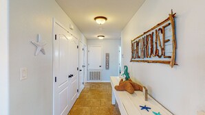 Un couloir avec des portes blanches, un banc avec des jouets et un élément décoratif mural.
