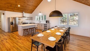 Une cuisine moderne dotée d’un îlot central, de planchers en bois et d’un coin repas aménagé pour accueillir 10 personnes.