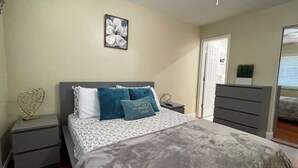 A bedroom with a bed, nightstands, a dresser, and a door.