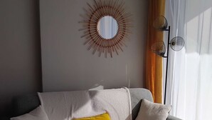 A living room with a sofa, a coffee table, a mirror, and a lamp. - Appartement Face MER - La Baule (LA BAULE ESCOUBLAC)