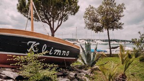 A boat named "Klimmo" docked at a marina with boats in the background and trees around.