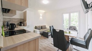 A modern kitchen with a built-in stove, a dining area with a table and chairs, and a sofa. - Holiday apartment Sara with sea views and pool (Klimno)