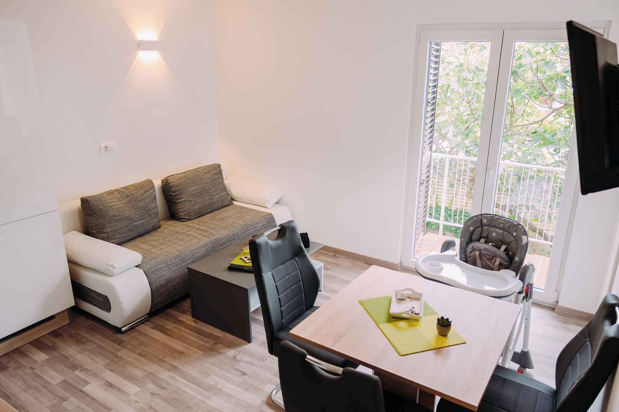 A compact living space with a sofa, a dining table, and a baby stroller.