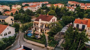 A residential area with houses featuring red-tiled roofs and a central house with a swimming pool and a covered outdoor area. - Holiday apartment with sea view and pool (Klimno)