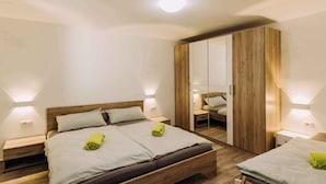 A modern bedroom with a wooden bed, bedside tables, a wardrobe, and wall-mounted lighting. - Holiday apartment with sea view and pool (Klimno)