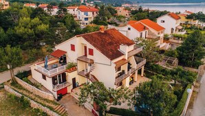 Un immeuble à plusieurs étages doté de balcons, entouré de verdure et offrant une vue sur la côte.