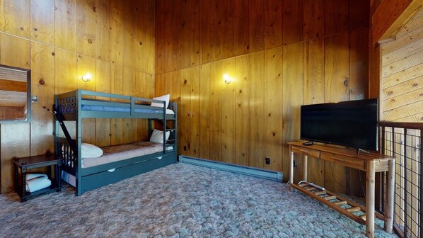 A wooden cabin room with bunk beds, a television, and a small table.