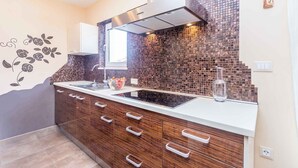 A modern kitchen with a black countertop, wooden cabinets, and a backsplash made of small tiles.