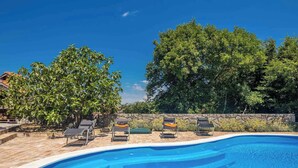 A swimming pool with lounge chairs and a stone wall.