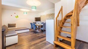 Uma sala de estar moderna com um sofá, uma área de jantar com cadeiras, uma televisão e uma escada de madeira.