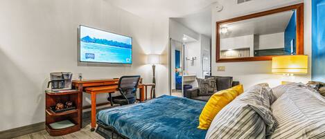 A hotel room with a bed, desk, chair, TV, and a mirror.