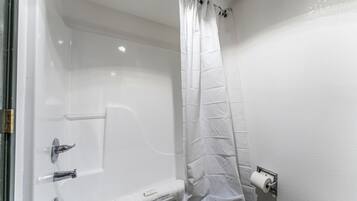 A bathroom with a white bathtub, a shower curtain, a toilet, and a towel rack.